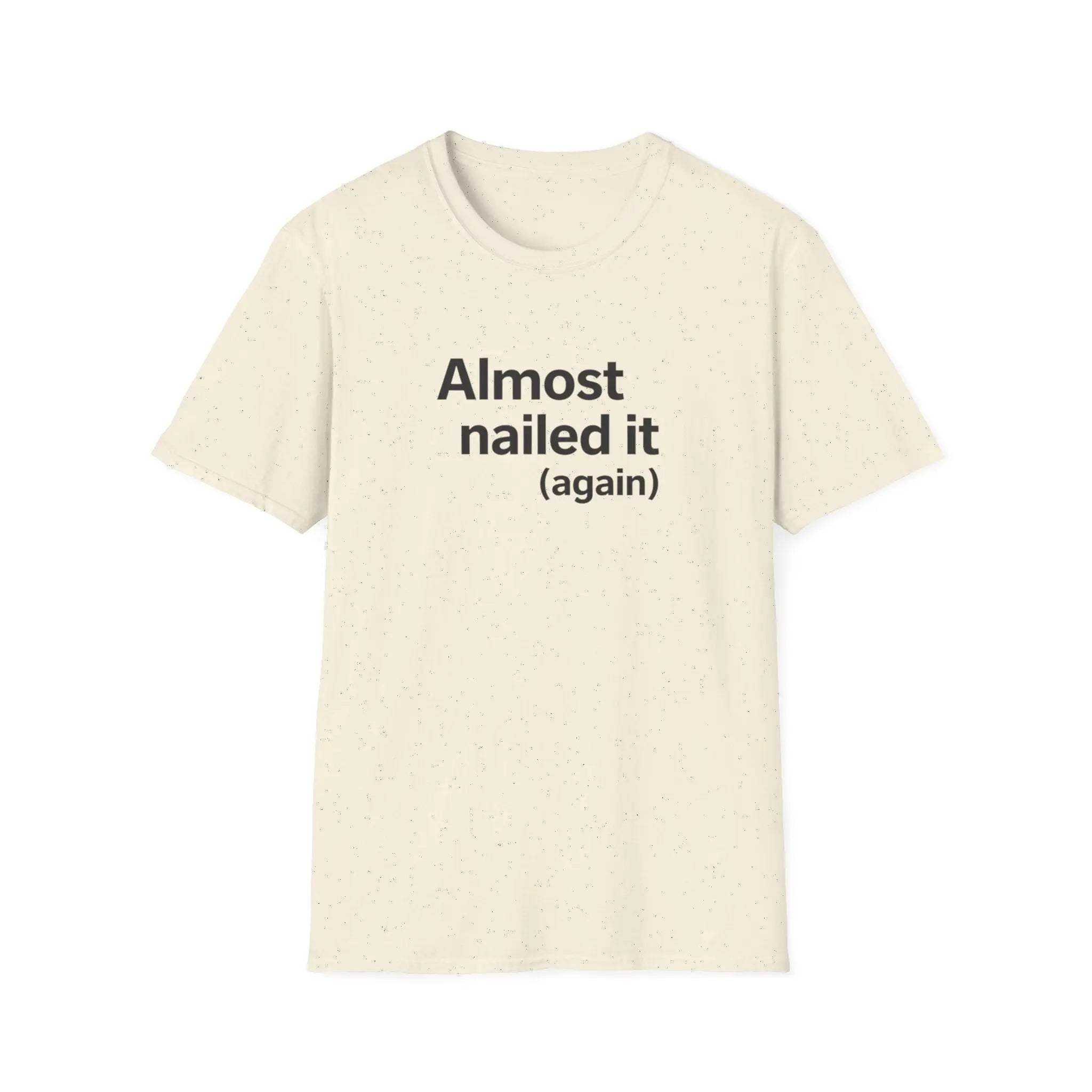 Beige t-shirt with text 'Almost nailed it (again)' on a white background